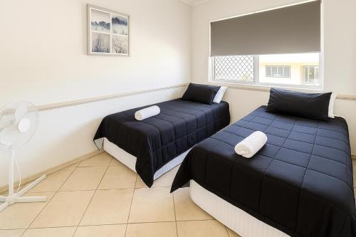a room with two beds and a fan at Redcliffe Villa in Redcliffe