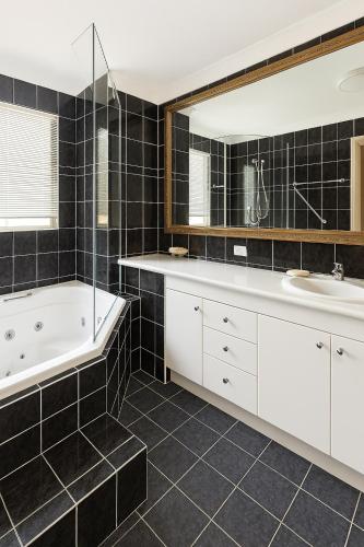 a bathroom with a white tub and a sink at Redcliffe Villa in Redcliffe