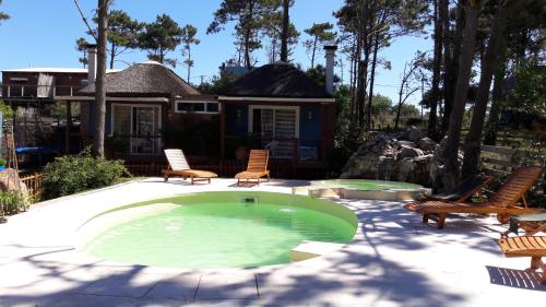a backyard with a pool with chairs and a house at Il Tano Suites in Punta Del Diablo