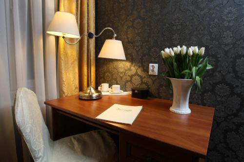 a desk with a vase of flowers and a lamp at Hotel Imperium in Chełmża