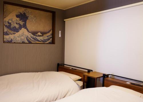 a room with two beds and a painting of a wave at マホロバハウス ペットも泊まれる1棟貸 in Tadotsu