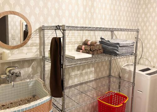 a bathroom with a shelf with towels and a mirror at マホロバハウス ペットも泊まれる1棟貸 in Tadotsu