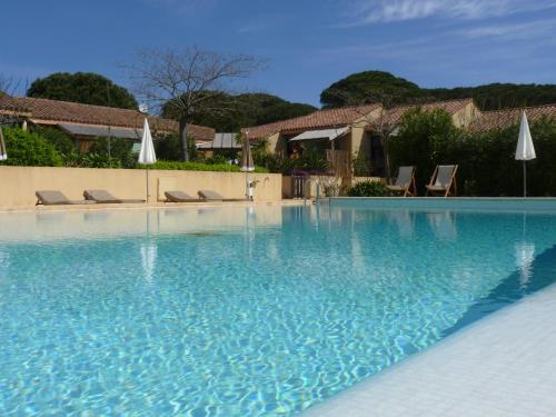 a swimming pool with blue water and chairs and umbrellas at Residence Les Sellettes in Saint-Tropez