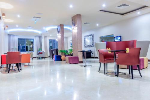 a lobby with red chairs and tables in a building at The Palms by Eagles in Takoradi