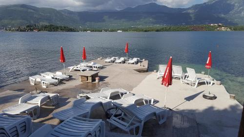 a group of chairs and umbrellas on a lake at Apartments Klakor PS in Tivat