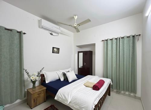 a bedroom with a bed with white walls and green curtains at Dream Nest Beach House in Alleppey
