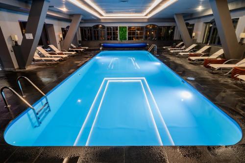 a swimming pool in a hotel lobby with lounge chairs at Q Resort and Spa in Săcele