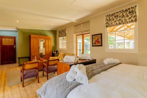 a bedroom with a large bed and a desk at Glen Eden Lodge in Lidgetton