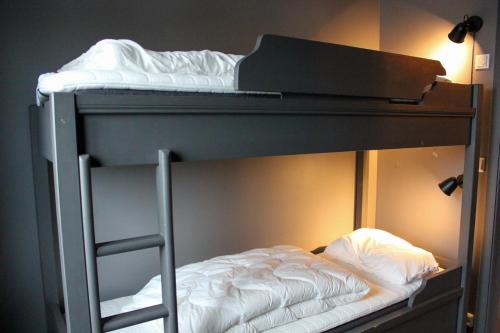 a bunk bed with white sheets and a ladder on it at Stølstunets samlingssted in Beitostøl