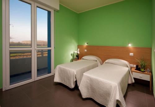 2 camas en una habitación con paredes y ventanas verdes en Hotel Ponte, en Colorno