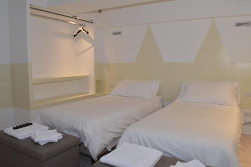 two beds in a room with white sheets at Appartamenti RHO in Rho