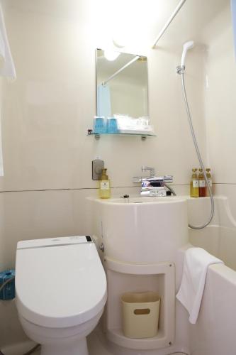 a bathroom with a toilet and a sink and a mirror at Hotel Sunshine Iwaki in Iwaki