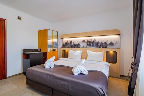a bedroom with a large bed with white shoes on it at Q Resort and Spa in Săcele