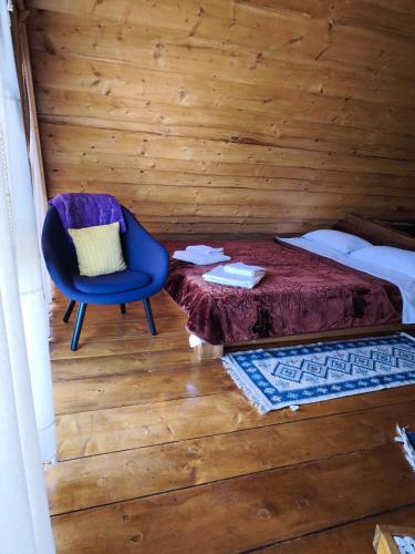 a bedroom with a bed and a blue chair at Noapte de Poveste in Piatra Fantanele
