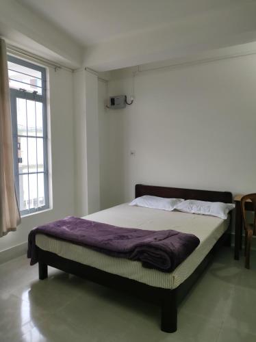 a bed in a room with a purple blanket on it at Windfall Homestay in Dimapur