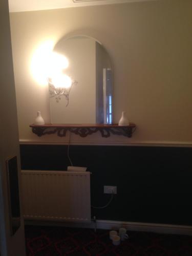 a bathroom with a mirror and a light on the wall at Lynebank House Hotel, Bed & Breakfast in Carlisle