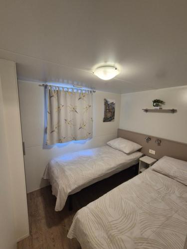 two beds in a small room with a window at Glamour Pakoštane Mobile Home in Pakoštane