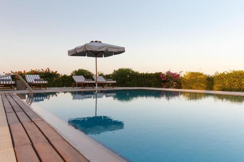 a swimming pool with an umbrella and two chairs at Belvedere Beachfront Villa in Afantou