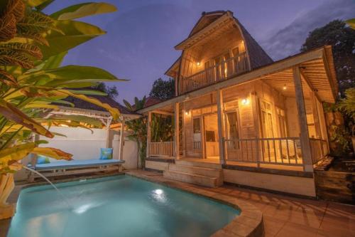 a house with a swimming pool in front of a house at Wana Shanti Villa in Bringkit