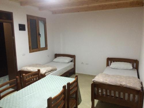 a room with two beds and a table and chairs at Buni Shqipes in Theth