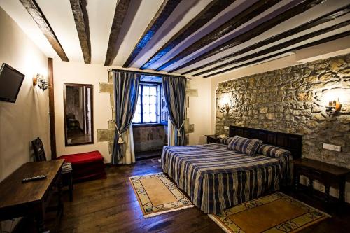 a bedroom with a bed and a stone wall at Hotel Altamira in Santillana del Mar