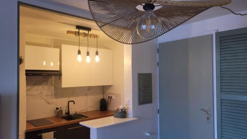 a kitchen with white cabinets and a ceiling fan at SERENATA - Studio climatisé sur le Port - Piscine & Tennis in Sausset-les-Pins