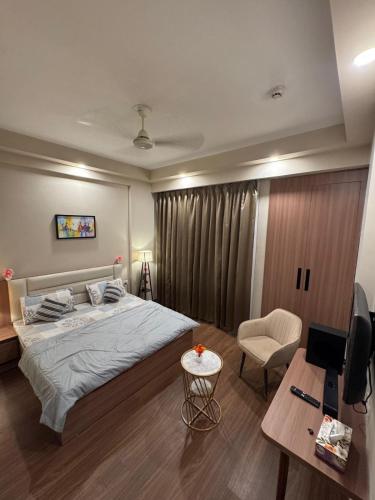 a bedroom with a bed and a desk and a television at Shagun Stays in Greater Noida