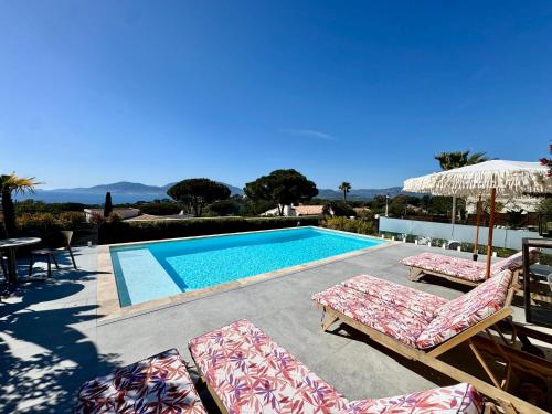 a swimming pool with two chairs and an umbrella at Domaine LUMISTELLA in Porticcio