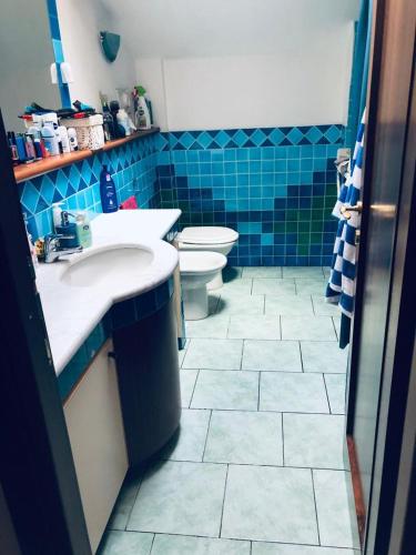 a bathroom with two sinks and a toilet and blue tiles at Casa Alma in Cogliate