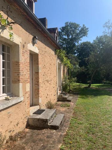 an old brick building with a door and a yard at Gîte Les Moreaux in Saint-Amand-en-Puisaye