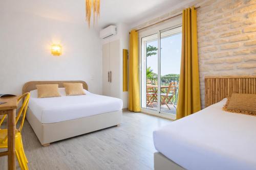 a bedroom with two beds and a balcony at Hôtel Almanarre Plage - Hôtel Eco-Responsable face à la mer in Hyères