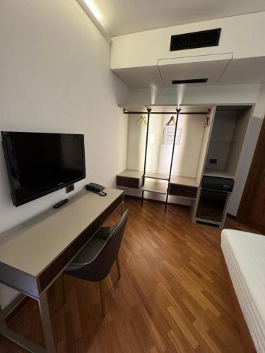 a room with a desk with a television and a bed at Hotel Baia Flaminia in Pesaro