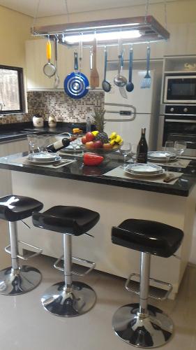 a kitchen with a counter with bar stools in it at Pousada Porto Paraiso, o seu Paraíso Escondido no Guarujá in Guarujá