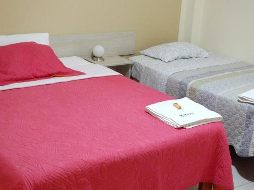 a hotel room with two beds with red blankets at Hostal Gazu in Chiclayo