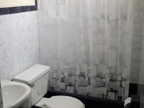 a bathroom with a toilet and a shower curtain at Hostal Gazu in Chiclayo
