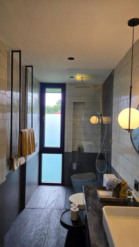 a bathroom with a sink and a toilet and a window at The Bataran Studio in Gitgit