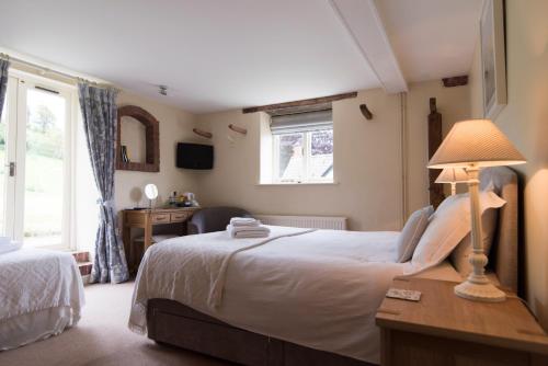 a bedroom with a bed and a desk and a window at The White Horse Inn in Calne