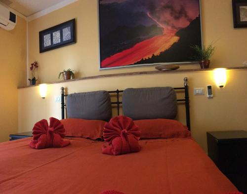 a bedroom with a red bed with red pillows at Tano's in Giardini Naxos