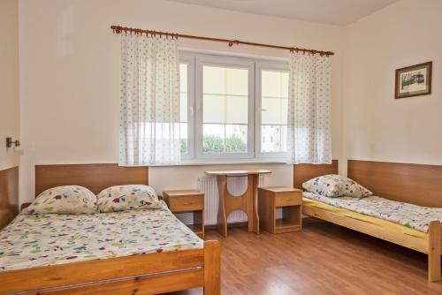 a room with two beds and a table and a window at Przystań u Kapitana in Ustka