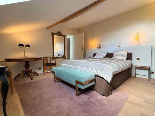 a bedroom with a large bed and a table at Les Suites du Midi in Saint-Paul-dʼEspis