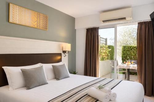 a bedroom with a bed with white pillows and a balcony at Logis Hotel Restaurant L'Escapade in Le Pêchereau