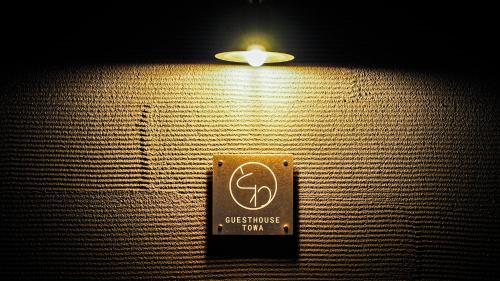 a light on a wall with a sign on it at ゲストハウスとわ in Kanazawa