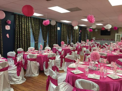 a room full of tables with pink and white table settings at Airport Inn in Nederland