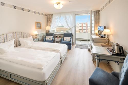 a hotel room with two beds and a desk at Hotel Wiking Sylt in Westerland