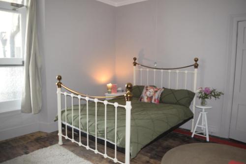 a bedroom with a white bed with a green comforter at Gorffwysfa Hideaway Double 1st floor in Pwllheli