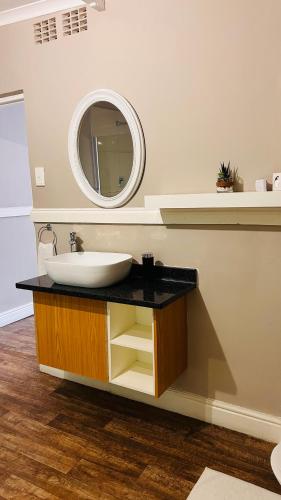 a bathroom with a sink and a mirror at Hidden Villas Guesthouse in East London