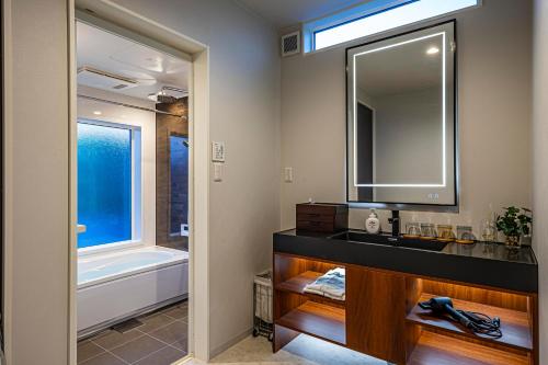 a bathroom with a sink and a mirror and a tub at Galaxy Pool Resort in Takashima