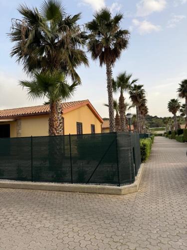 a fence with palm trees in front of a house at Residence Hydria in Campofelice di Roccella