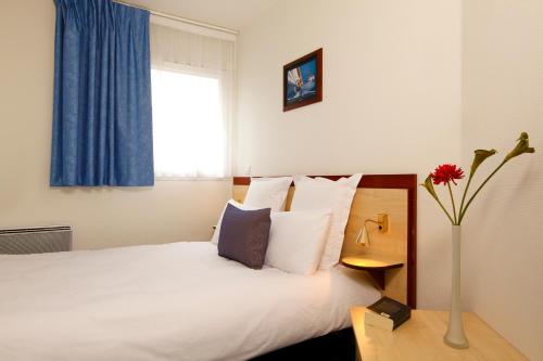 a hotel room with a bed and a vase of flowers at Appart'City Classic Clermont Ferrand Centre in Clermont-Ferrand