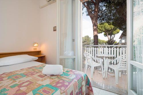 a bedroom with a bed and a balcony with a table and chairs at Hotel Milena in Cervia